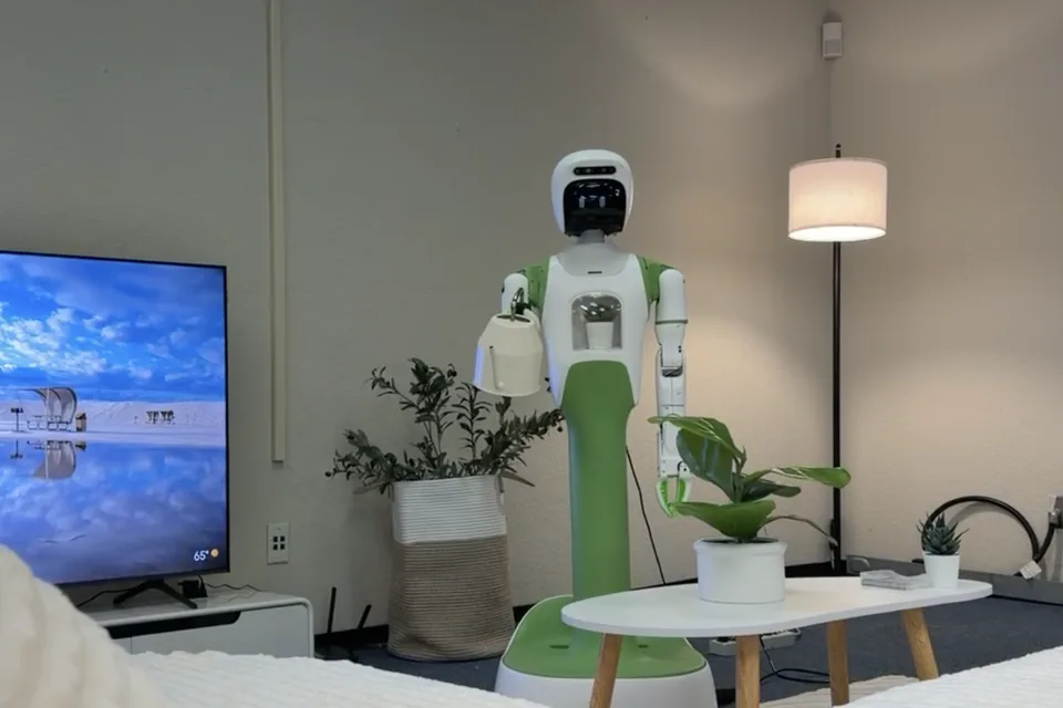 KOKO stands in a test living room with a television, a sofa, and a floor lamp.